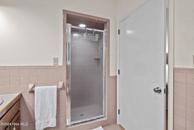 bathroom with an enclosed shower, vanity, and tile walls