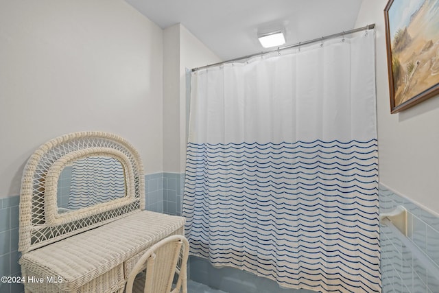 bathroom featuring walk in shower and tile walls