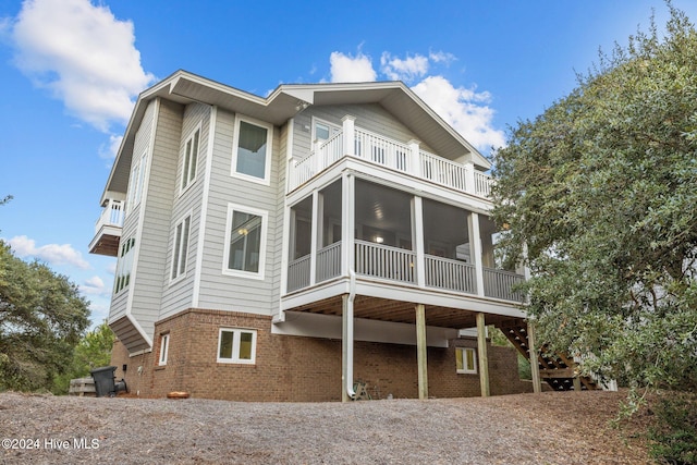 back of property featuring a sunroom and a balcony