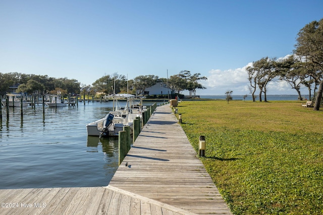 view of dock featuring a lawn and a water view