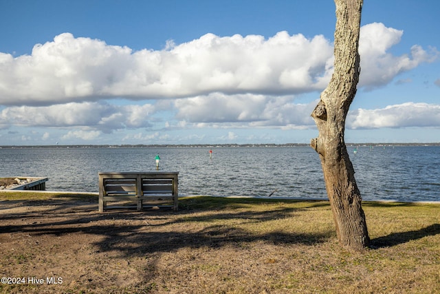 view of dock with a lawn and a water view