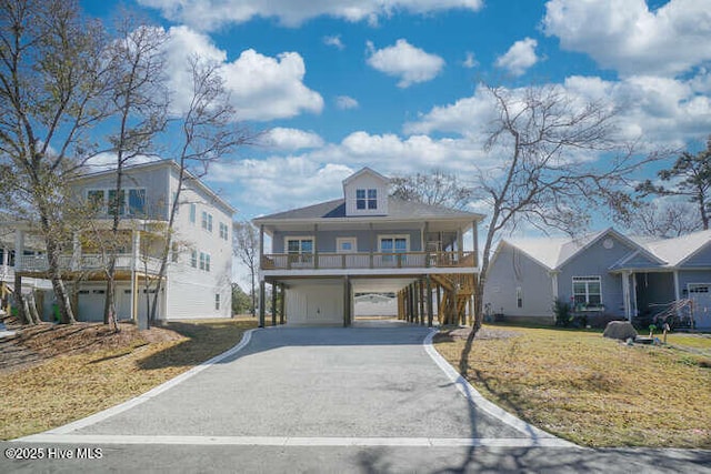 coastal home with a carport, covered porch, a front yard, and driveway