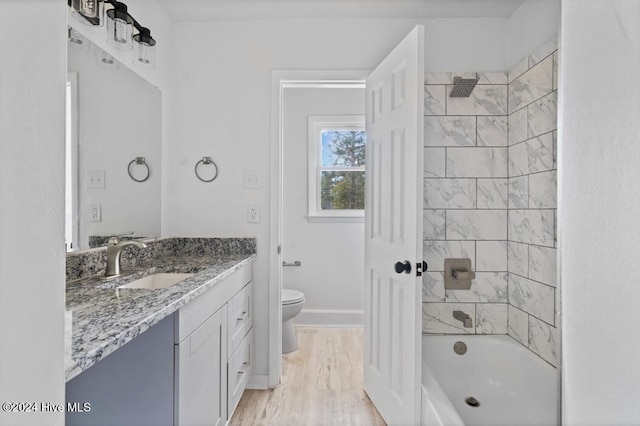 full bathroom featuring hardwood / wood-style flooring, vanity, toilet, and tiled shower / bath