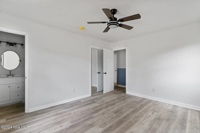 unfurnished bedroom featuring ensuite bathroom, ceiling fan, light wood-type flooring, and sink