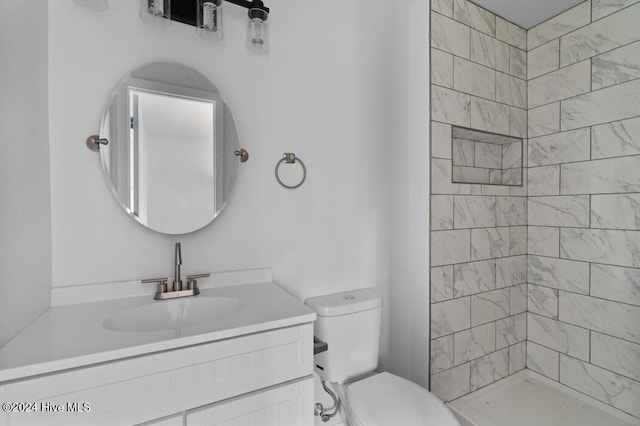 bathroom featuring tiled shower, vanity, and toilet