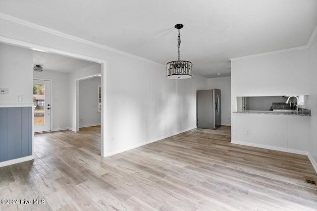 unfurnished dining area featuring sink, light wood-type flooring, and crown molding