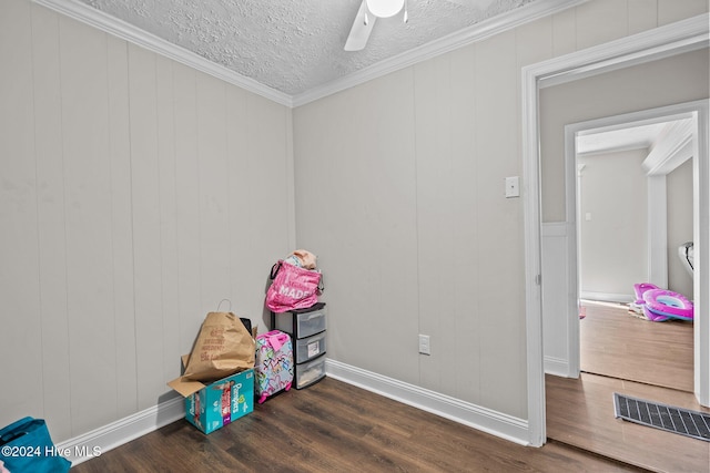 rec room with a textured ceiling, ceiling fan, ornamental molding, and dark wood-type flooring