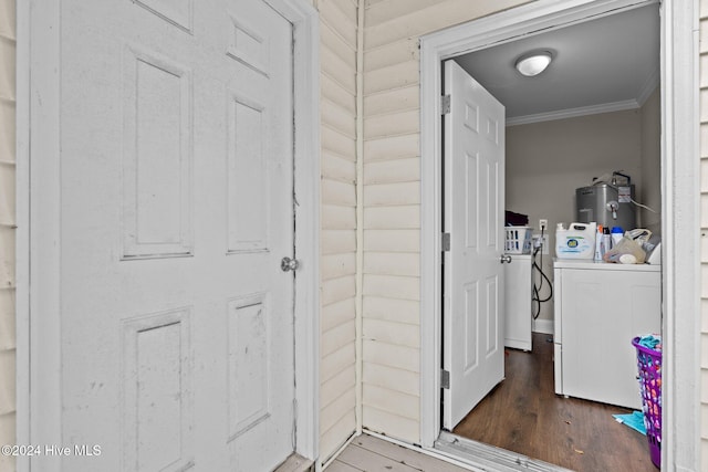 washroom with washing machine and clothes dryer, electric water heater, dark hardwood / wood-style flooring, and ornamental molding