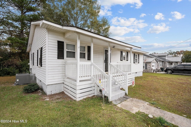 view of front of home featuring central AC unit, a porch, and a front lawn