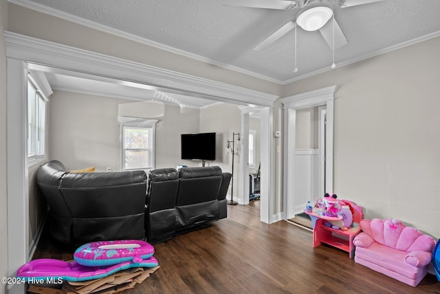 living room with ornamental molding, a textured ceiling, ceiling fan, and dark wood-type flooring