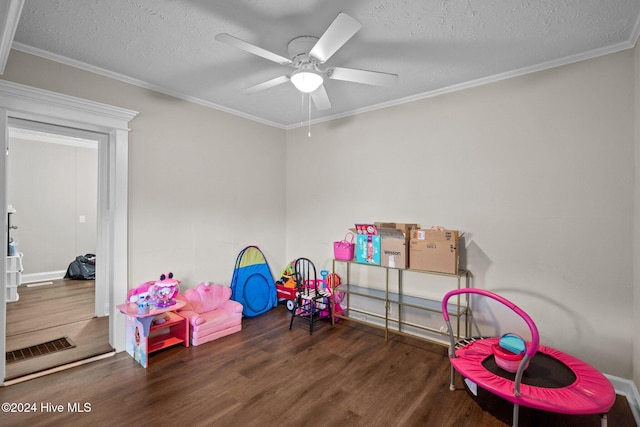 rec room with a textured ceiling, dark hardwood / wood-style flooring, ceiling fan, and ornamental molding