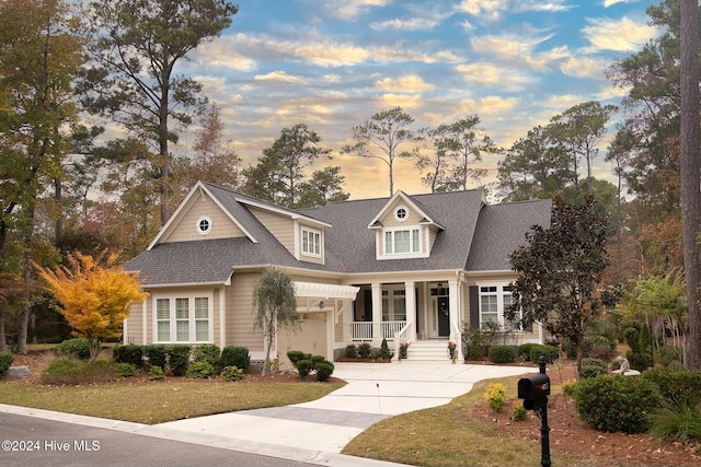 view of front facade with a garage, covered porch, and a lawn