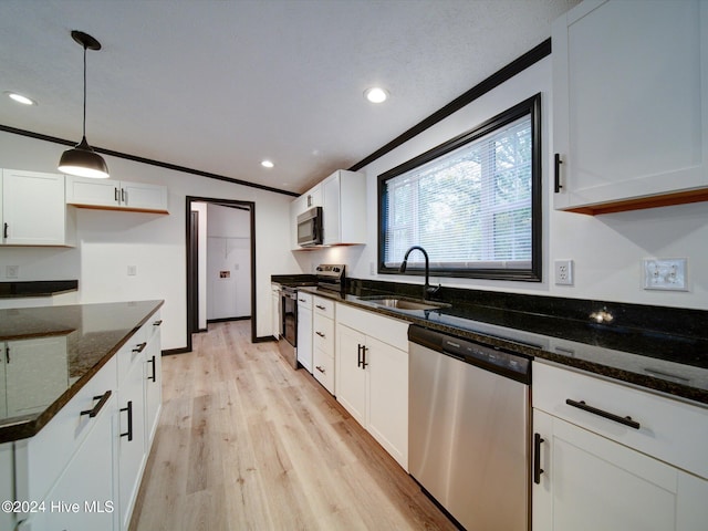 kitchen with light wood-type flooring, stainless steel appliances, sink, pendant lighting, and white cabinetry