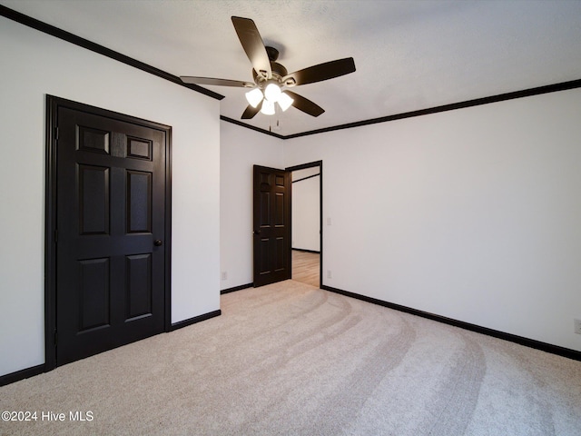 unfurnished bedroom featuring a textured ceiling, ceiling fan, ornamental molding, and light carpet