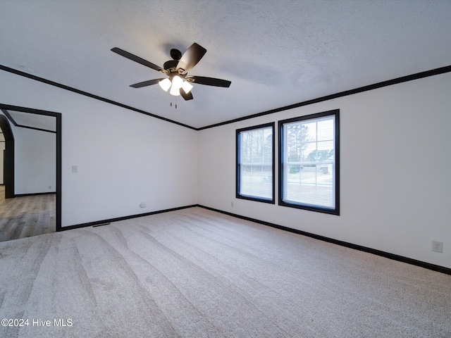 carpeted empty room with ceiling fan, ornamental molding, and a textured ceiling