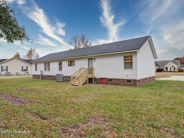 rear view of house featuring cooling unit and a lawn