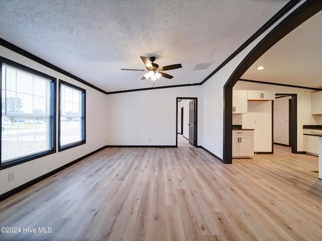 unfurnished room with ornamental molding, a textured ceiling, and light hardwood / wood-style flooring