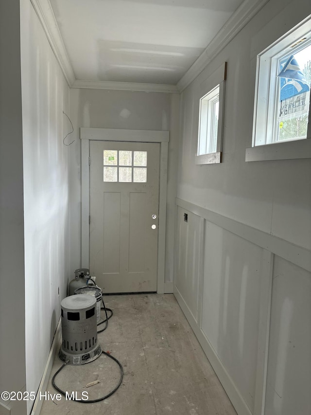 entryway featuring a wainscoted wall, ornamental molding, and a decorative wall