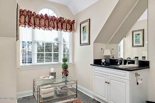 kitchen with lofted ceiling, white cabinetry, and sink