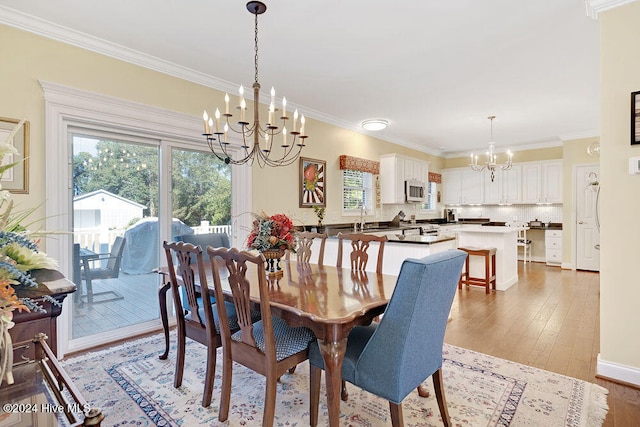 dining space with crown molding, hardwood / wood-style floors, sink, and a notable chandelier