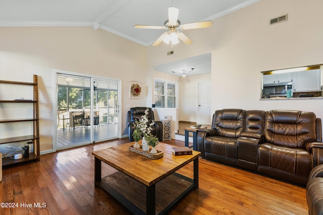 living room with beam ceiling, high vaulted ceiling, crown molding, ceiling fan with notable chandelier, and light wood-type flooring