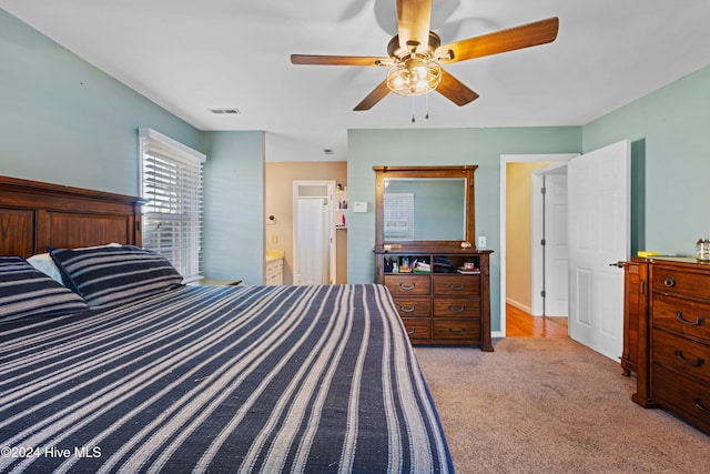 bedroom with connected bathroom, ceiling fan, and light carpet