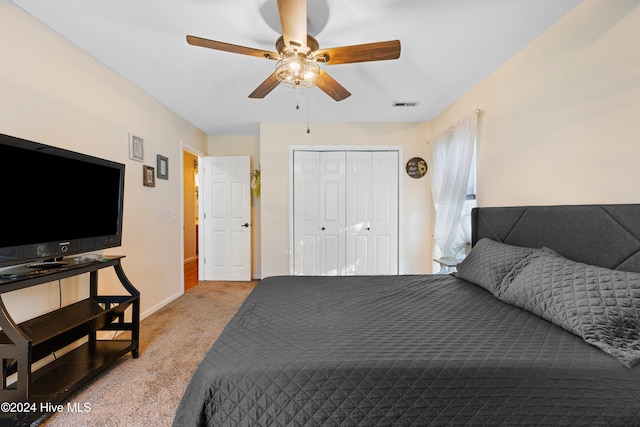 bedroom with ceiling fan, light colored carpet, and a closet