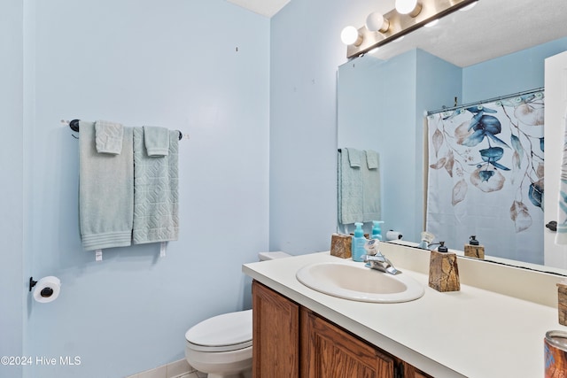 bathroom with vanity, curtained shower, toilet, and a textured ceiling