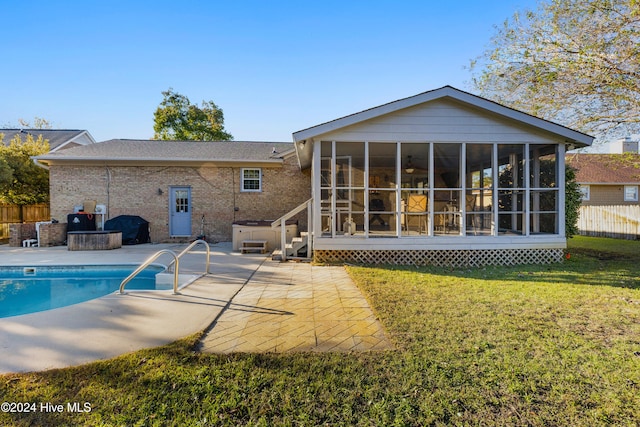 rear view of house featuring a sunroom, a swimming pool with hot tub, a patio area, and a yard