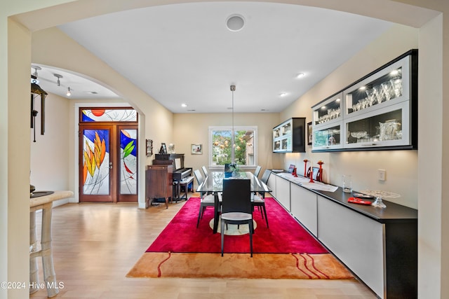 dining area featuring arched walkways and light wood-style floors