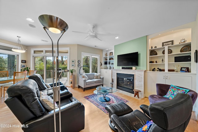 living room featuring plenty of natural light, wood finished floors, a fireplace, and ceiling fan