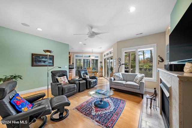 living room with ceiling fan, a fireplace, and light hardwood / wood-style floors