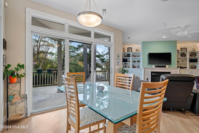 dining area featuring a high end fireplace, plenty of natural light, light wood finished floors, and ceiling fan