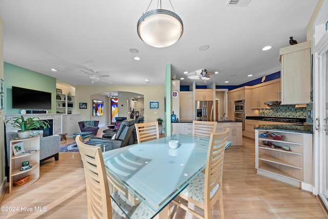 dining space featuring light wood-type flooring, ceiling fan, and sink