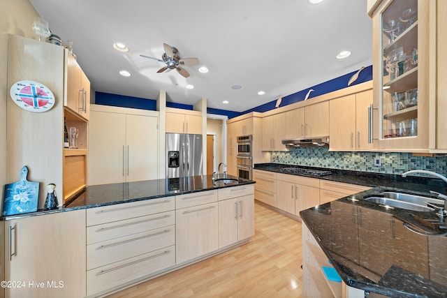 kitchen featuring light brown cabinetry, stainless steel appliances, backsplash, a ceiling fan, and a sink