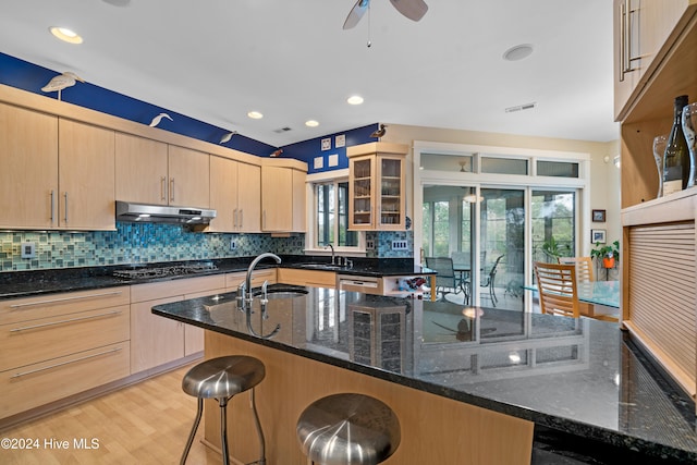 kitchen with dark stone counters, a breakfast bar area, a healthy amount of sunlight, and sink