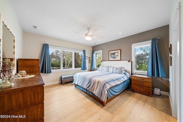 bedroom with light wood-type flooring, multiple windows, and ceiling fan