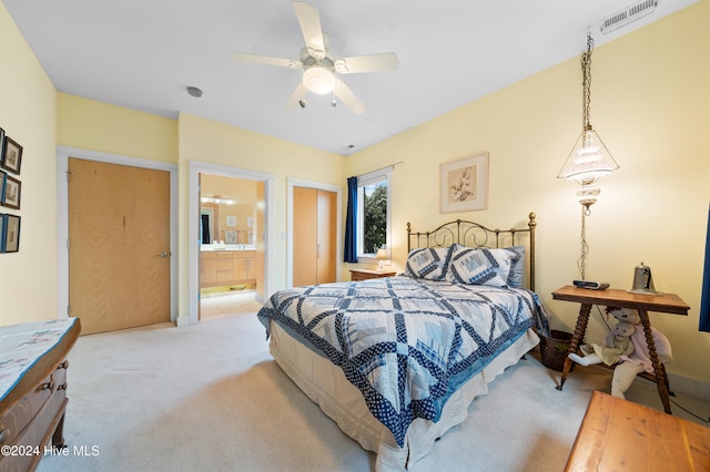 carpeted bedroom with ensuite bathroom and ceiling fan