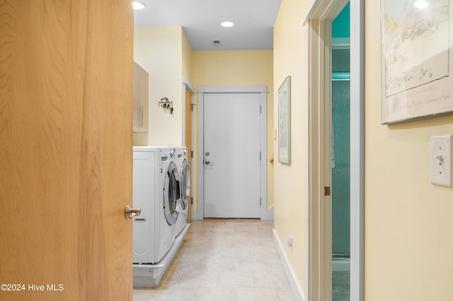 laundry room featuring washing machine and dryer, light tile patterned flooring, and cabinets