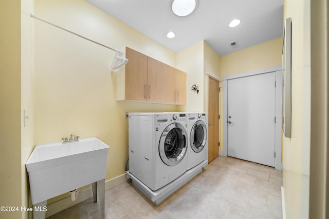laundry room featuring a sink, light tile patterned floors, washer and dryer, cabinet space, and visible vents