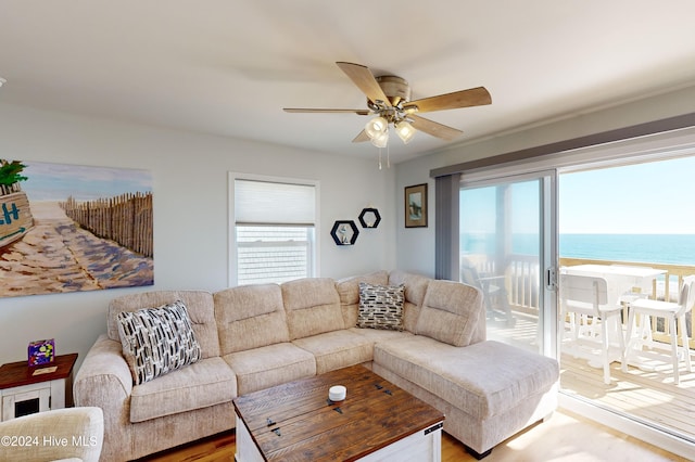 living room featuring ceiling fan, hardwood / wood-style floors, a water view, and a healthy amount of sunlight