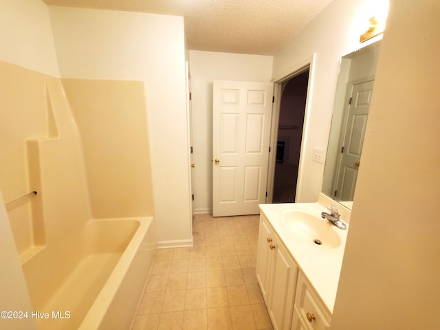 bathroom with a tub to relax in, tile patterned floors, vanity, and a textured ceiling