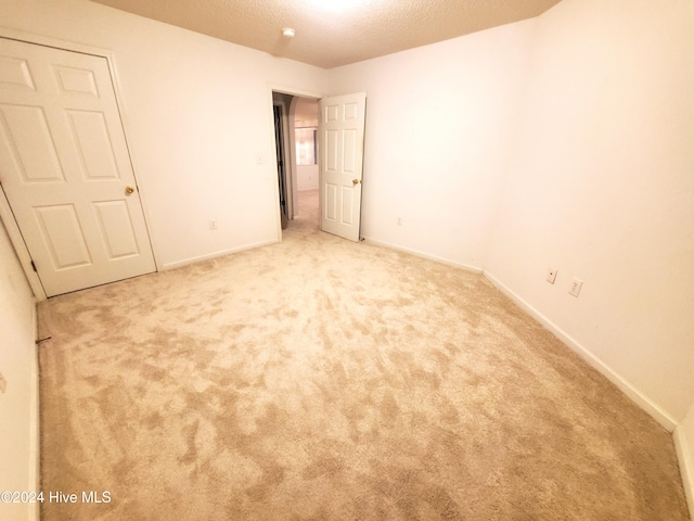 unfurnished bedroom featuring a textured ceiling and light colored carpet