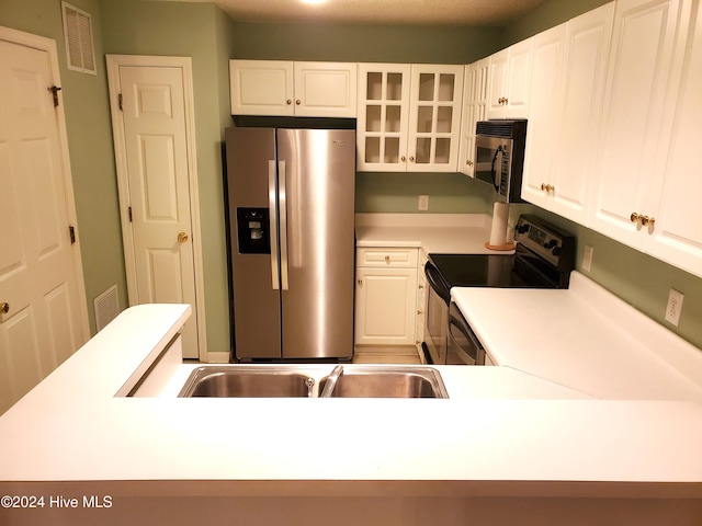 kitchen featuring kitchen peninsula, white cabinetry, stainless steel appliances, and a textured ceiling