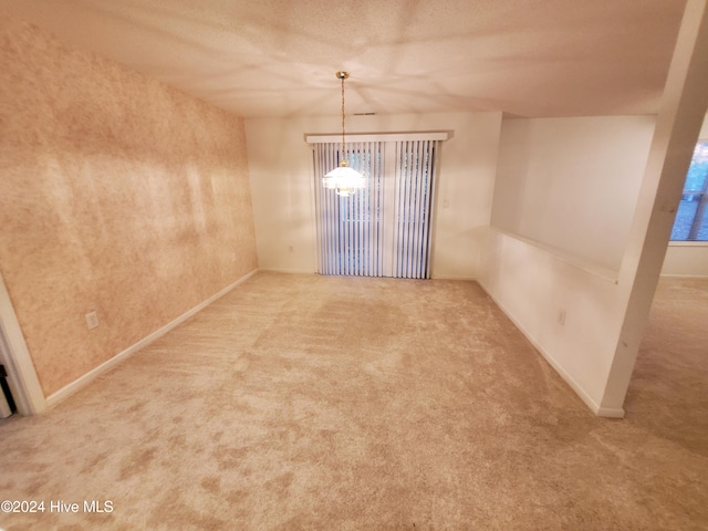 carpeted spare room featuring a chandelier and a textured ceiling