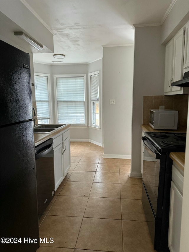 kitchen with light tile patterned floors, tasteful backsplash, crown molding, white cabinets, and black appliances