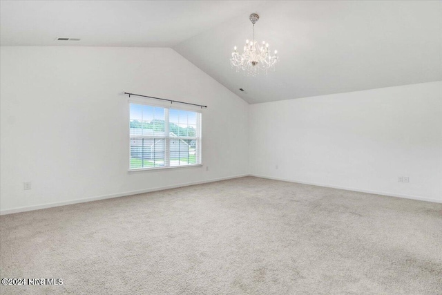 carpeted spare room with lofted ceiling and a notable chandelier