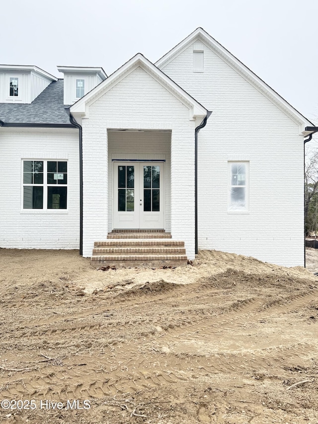 view of front facade with entry steps, french doors, and brick siding