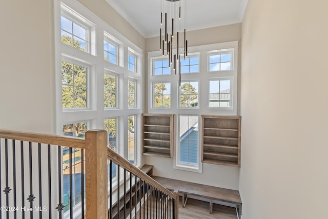 staircase featuring hardwood / wood-style flooring, crown molding, and a chandelier