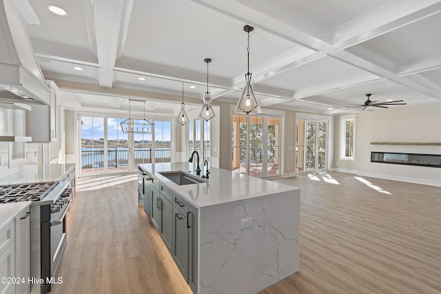 kitchen with ceiling fan, sink, decorative light fixtures, a water view, and custom exhaust hood